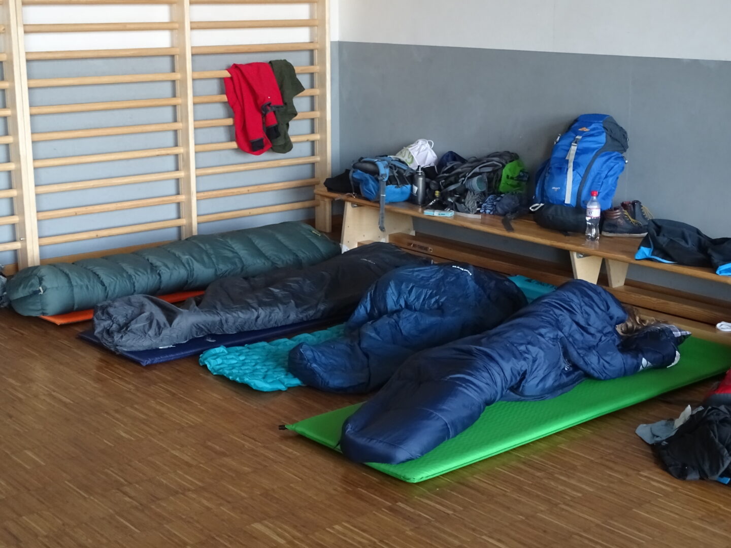 Vier Schlafsäcke und Isomatten in Sportraum als Schlafplatz